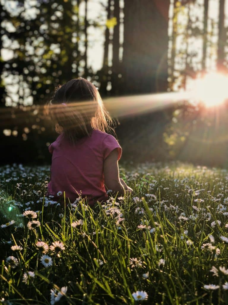 My family was enjoying some time on a hike in a wooded area. The way the light was coming through the trees and across the grass and daisies was making me itch to capture the moment. I got down on my stomach in the grass to capture this photo of my daughter Ellie. All I had with me that day was my iPhone X which was still a champ for captuing the moment perfectly. I just love the way the end of the day sunlight was making her glow. To me this photo perfectly captures summer, childhood, and my sweet girl, who shines brighter then the sun.